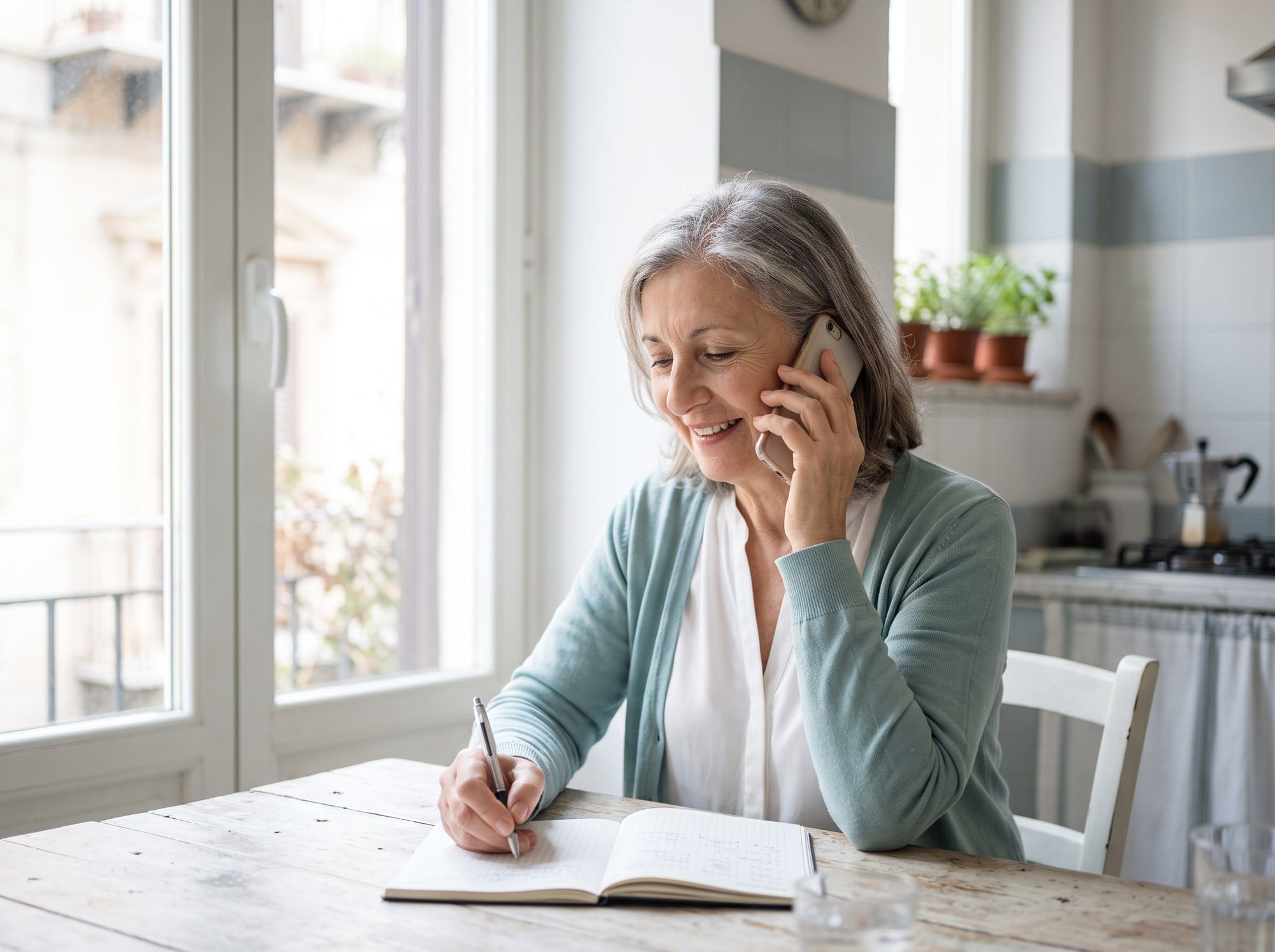 Paziente al telefono mentre segna un appuntamento sull’agenda